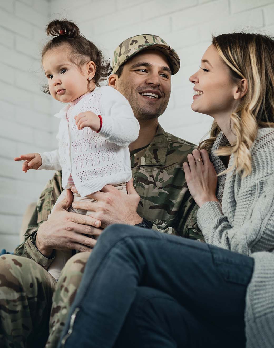 A military family of three smiles together.