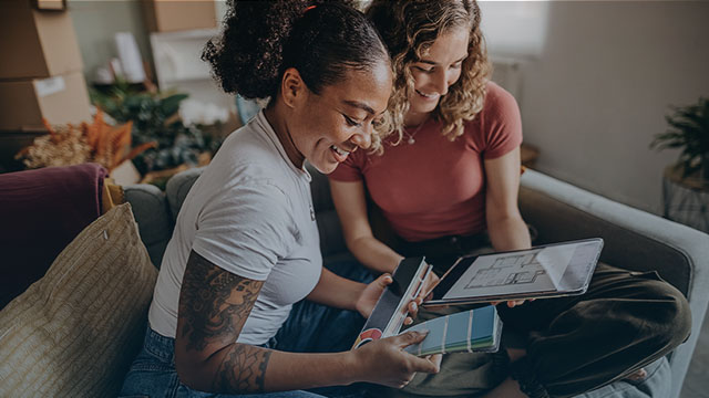 A couple smile together while browsing paint swatches.