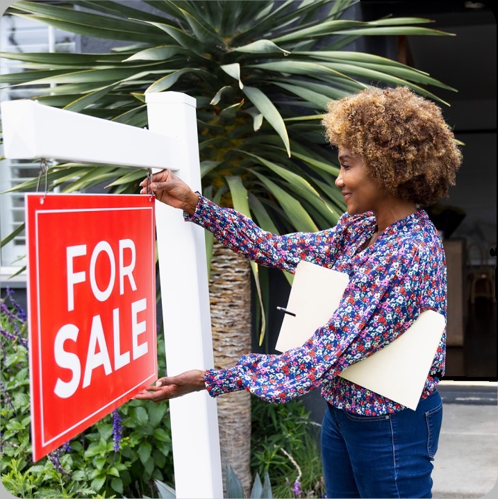 Realtor putting up for sale sign on dream home